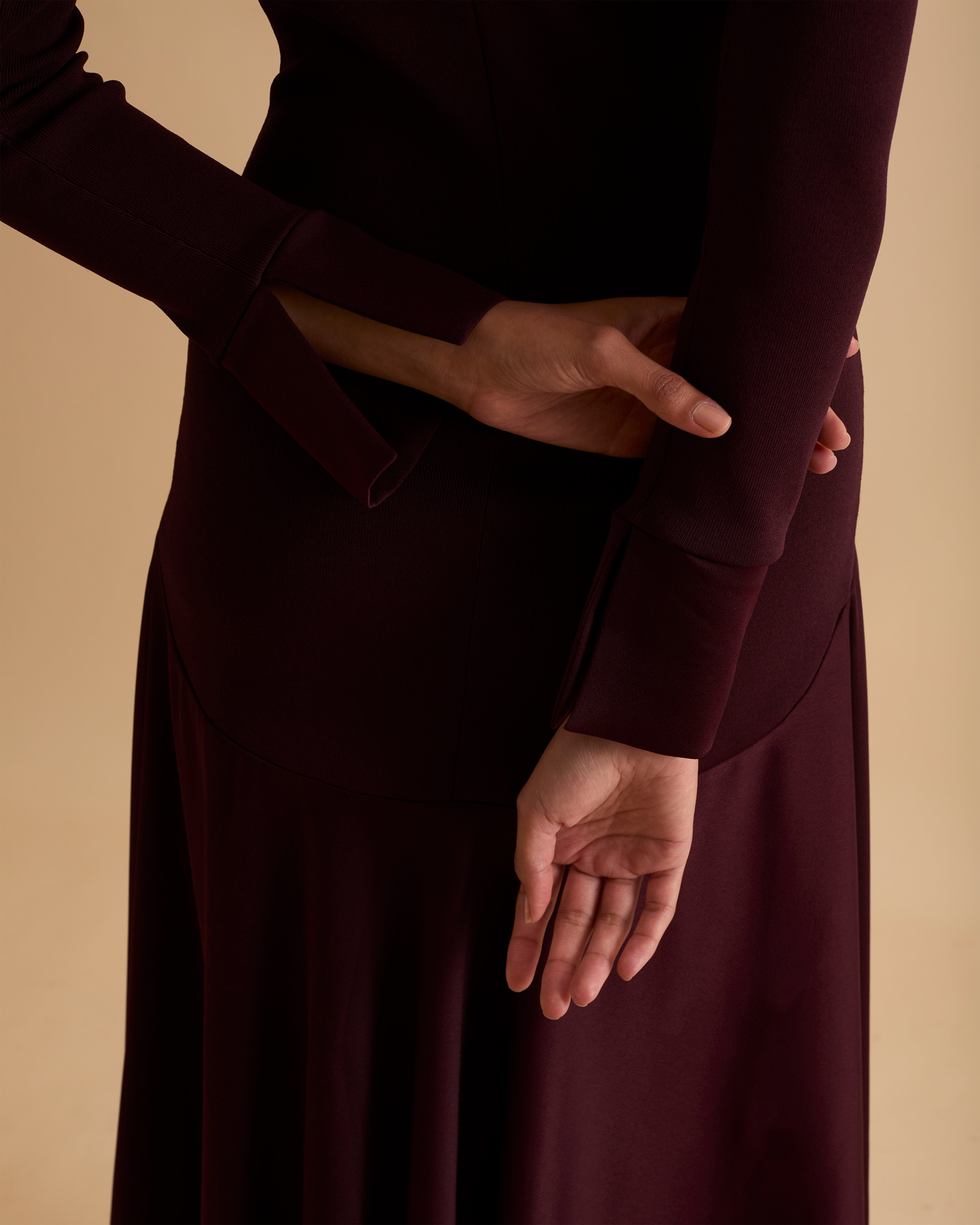 Model wearing Florere iconic signature Acacia dress. Knitted fabric for a fitted bodice, with dropped waist satin midi skirt with dramatic flare. Wearing tan knee high boots, against a beige neutral backdrop